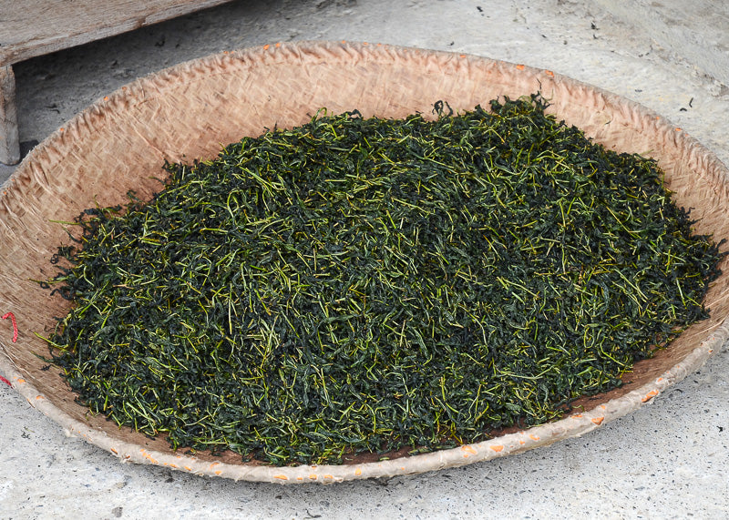 green loose leaf tea leaves in bamboo basket